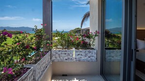 A balcony with a view of a golf course and mountains, featuring white planter boxes with pink flowers. - Porta Fortuna (Punta de Mita)