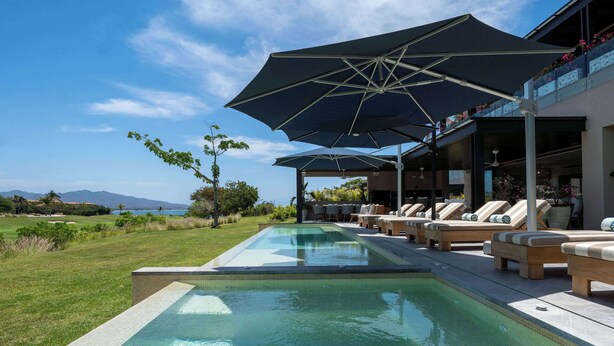A swimming pool with lounge chairs and umbrellas, overlooking a golf course and mountains. - Porta Fortuna (Punta de Mita)