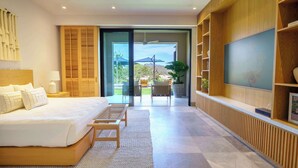 A modern bedroom with a large bed, a TV, and a sliding glass door leading to a balcony with outdoor furniture. - Porta Fortuna (Punta de Mita)