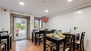 Un comedor con varias mesas y sillas, una zona de cocina y vistas al patio exterior.