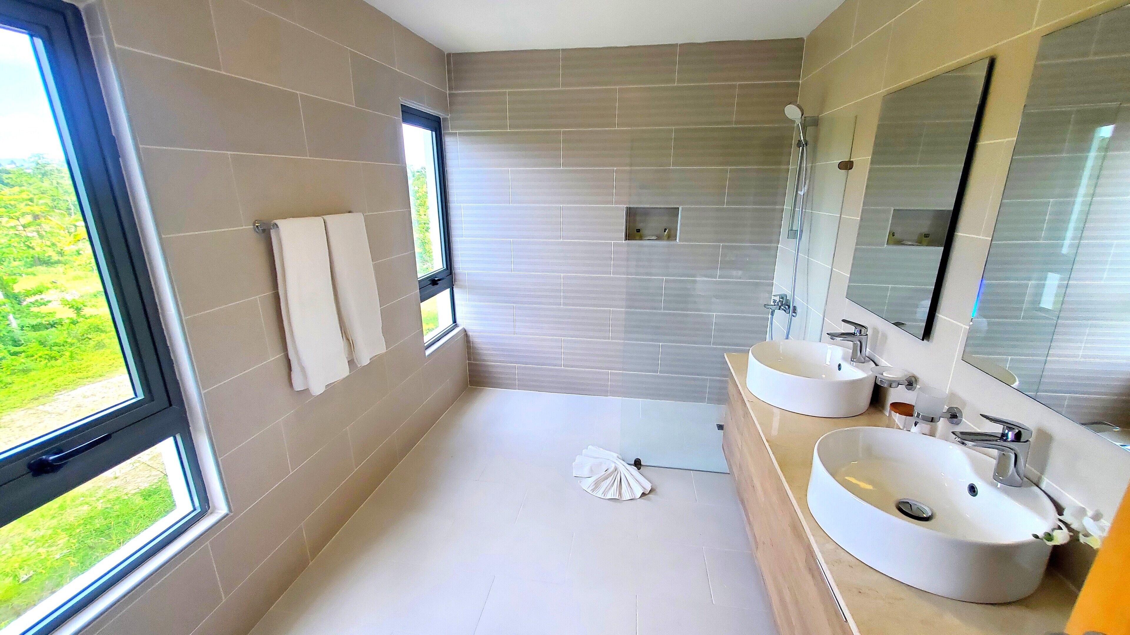 Een moderne badkamer met twee wastafels, een grote spiegel en een douche.