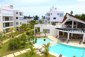 A resort with a swimming pool, multiple balconies, and outdoor seating areas. - Amare Beachfront Aparthotel (Las Terrenas)