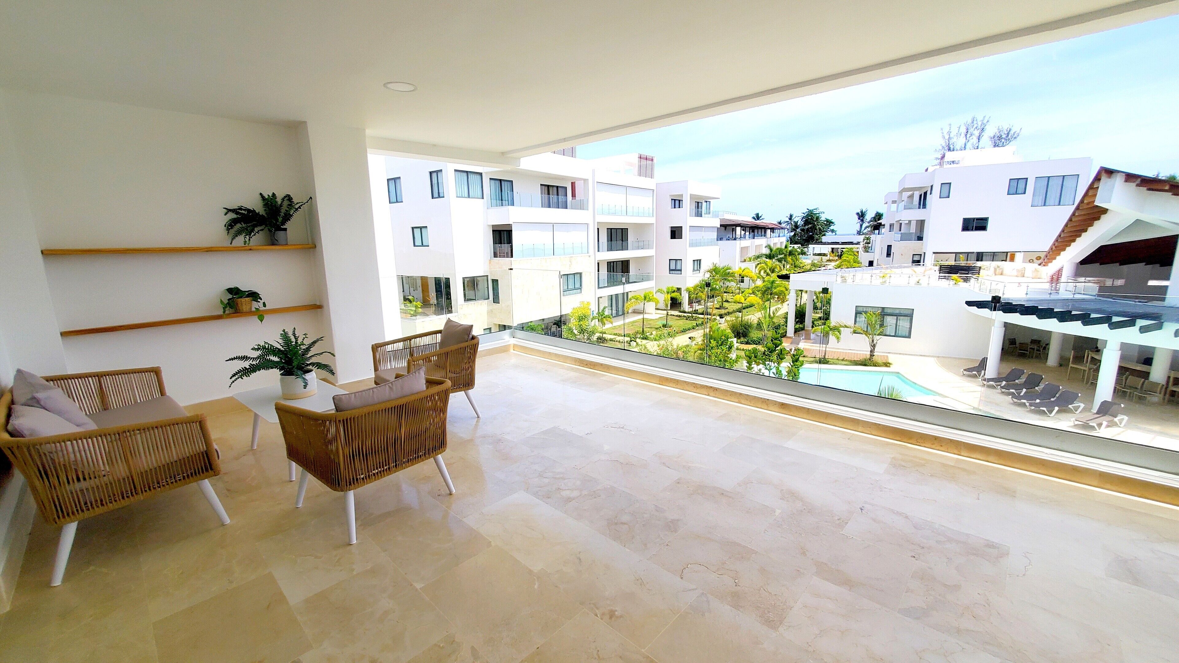 Ein geräumiger Balkon mit Blick auf einen Pool und umliegende Gebäude.