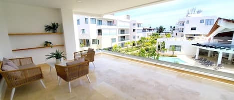 Ein geräumiger Balkon mit Blick auf einen Pool und umliegende Gebäude.