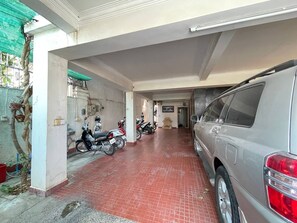 A covered parking area with a car and motorcycles parked. - Combretrata (Phnom Penh)