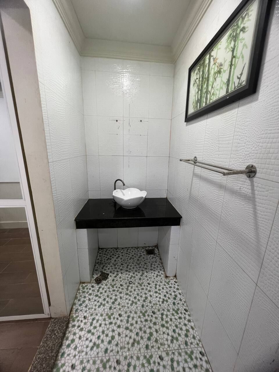 Un baño pequeño con lavamanos blanco, un espejo y un cuadro en la pared.