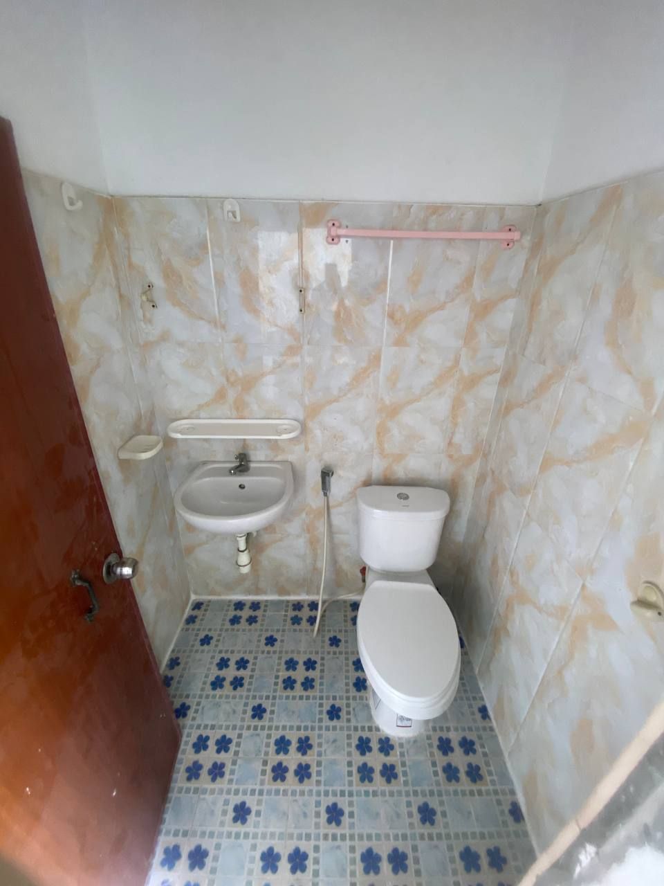A small bathroom with a toilet, sink, and a towel rack.