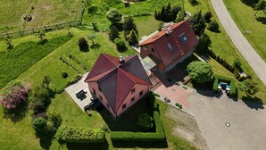 Ovenfra set et byggeri med røde tage, en belagt indkørsel og en velplejet græsplæne.