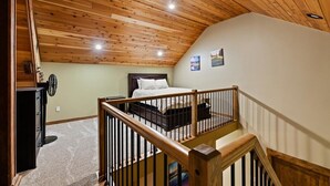 A bedroom with a wooden ceiling, a bed, a nightstand, and a dresser. - Lookout Lodge at Cavanaugh's (Coolin)