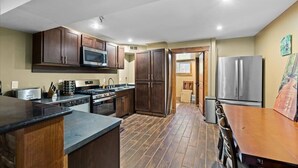 A kitchen with dark wooden cabinets, stainless steel appliances, and a tiled floor. - Lookout Lodge at Cavanaugh's (Coolin)