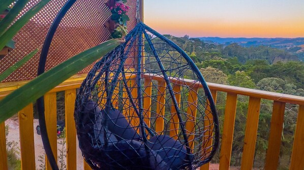 Una silla colgante en un balcón con vista a un paisaje montañoso.