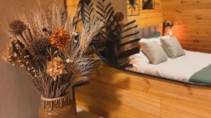A cozy room with a bed, pillows, and a decorative arrangement of dried plants and flowers. - Chalés Laraland (Campos do Jordão)