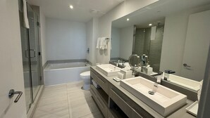 A modern bathroom with a glass shower enclosure, a bathtub, a toilet, and a vanity with a large mirror. - 2201 (Hollywood)