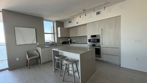 A modern kitchen with a central island, bar stools, and built-in appliances. - 2201 (Hollywood)