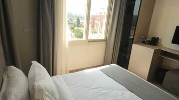 Una habitación de hotel con una cama grande, un escritorio y una ventana con cortinas.