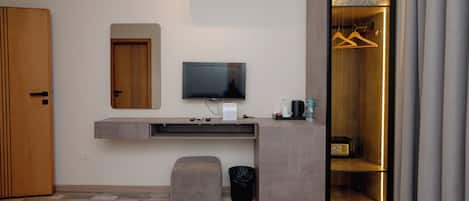 Une chambre moderne équipée d’une télévision intégrée, d’une armoire et d’un petit coin salon.
