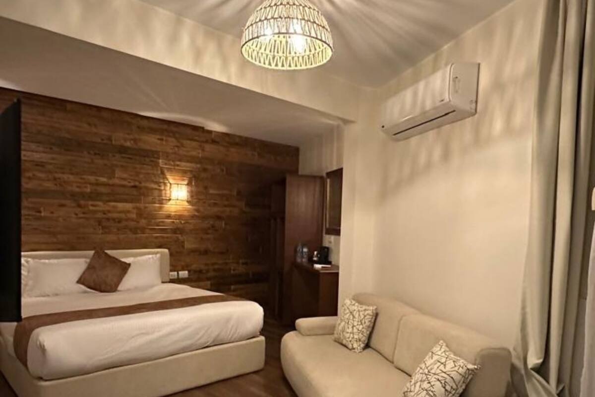 Una camera da letto moderna con una parete in legno decorativa, un letto, un divano e un lampadario.