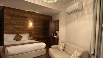 Quarto moderno com parede de destaque em madeira, uma cama, um sofá e um lustre.