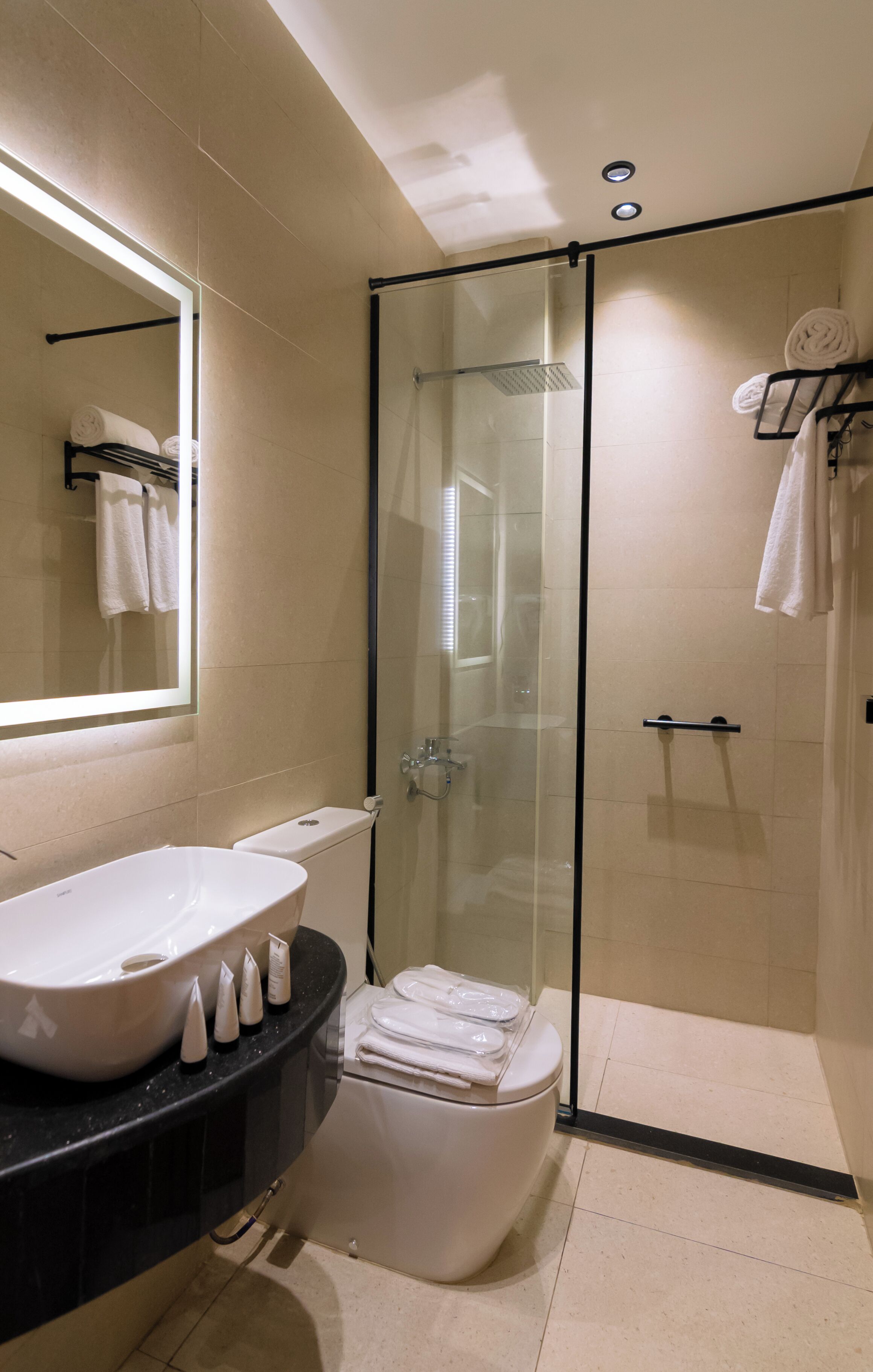 A modern bathroom with a glass-enclosed shower, a white sink, and a black countertop.