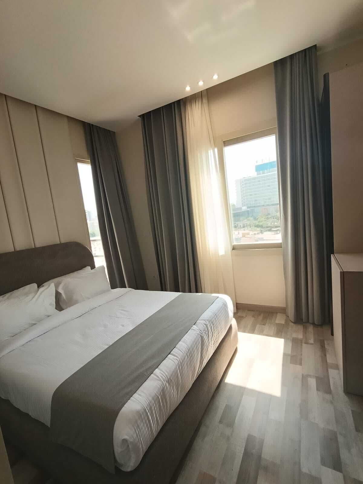 Una habitación de hotel moderna con una cama grande, un escritorio y una ventana con cortinas.
