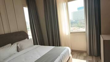 Una habitación de hotel moderna con una cama grande, un escritorio y una ventana con cortinas.