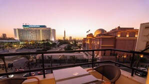 A balcony with a table and chairs overlooking a cityscape at dusk. - Elevana Boutique hotel (Cairo)