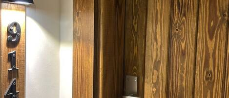 A wooden door with a numeric keypad lock, a small shelf, and a wall-mounted light fixture.
