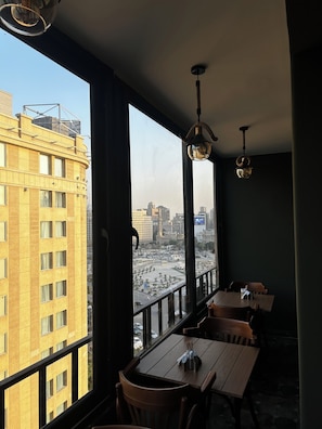 Una habitación con ventanas amplias, un balcón y una mesa con sillas.