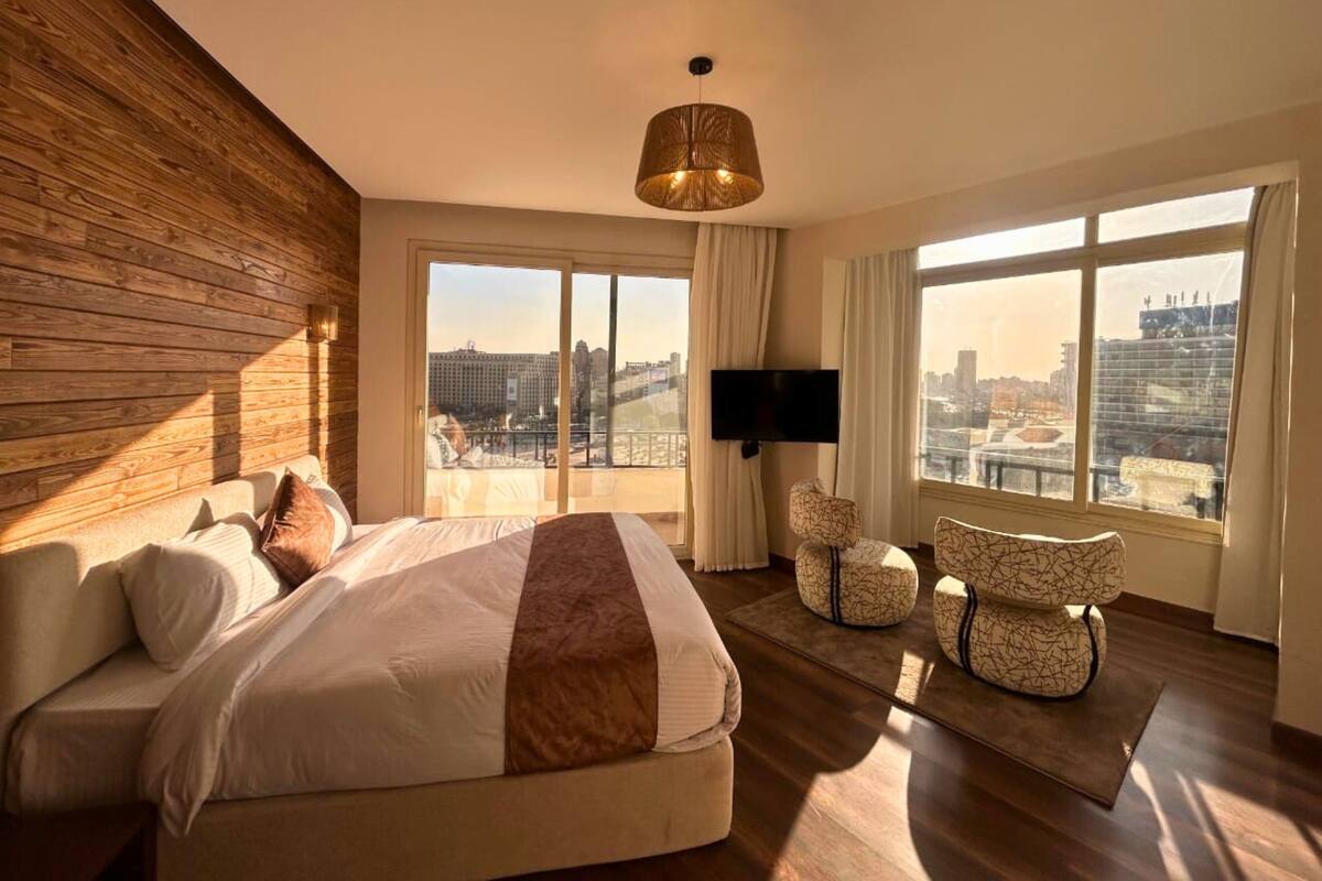 Una camera d'albergo moderna con un letto grande, una TV e vista sulla città.