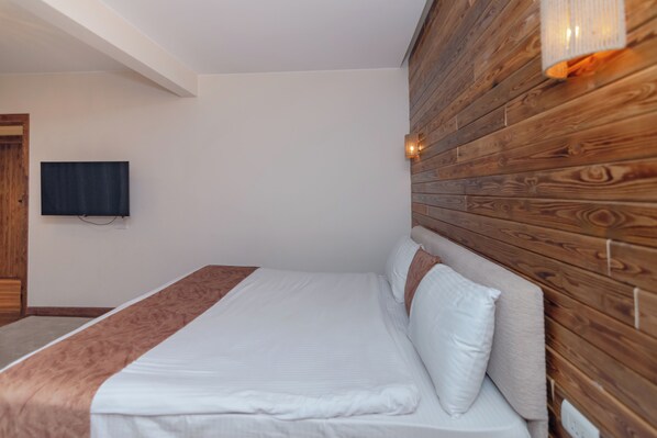 Deluxe Junior Suite | Ylelliset vuodevaatteet, minibaari, tallelokero huoneessa, työpöytä