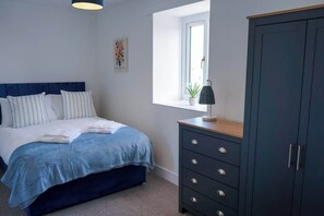 Un dormitorio con cama, cómoda, ventana y puerta.