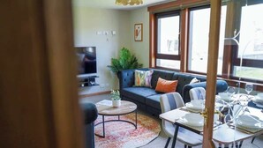 Un espacio de estar con sofá, mesa de centro y mesa de comedor dispuesta con platos y vasos.