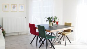 Ein Essbereich mit Tisch, Stühlen, einer Topfpflanze und gerahmten Kunstwerken an der Wand.