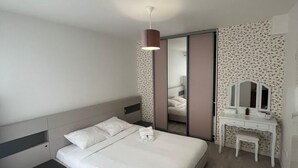 Ein modernes Schlafzimmer mit Bett, Nachttisch, Kommode und Spiegel.