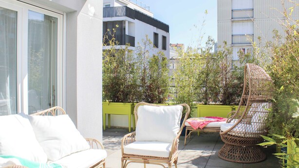 Ein Balkon mit Korbmöbeln, darunter eine Couch und Stühle, sowie ein kleiner Tisch.