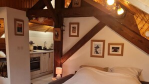 A bedroom with a large bed, wooden beams, and framed pictures on the wall. - 50m from resort center, 3rd floor, balcony, parking, tv, ski locker, 25m², Le Grand Bornand (Le Grand-Bornand)