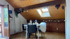 A dining area with a wooden ceiling, a skylight, and a white table with chairs. - 50m from resort center, 3rd floor, balcony, parking, tv, ski locker, 25m², Le Grand Bornand (Le Grand-Bornand)