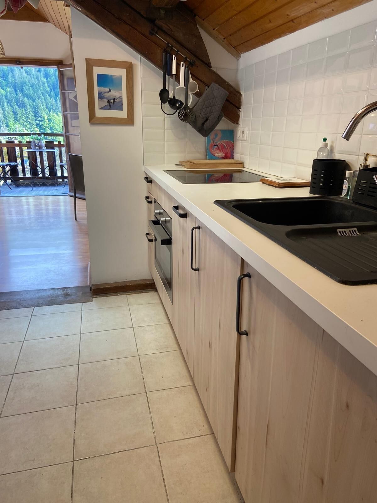 A kitchen with a wooden countertop, a black sink, and a view of a balcony with outdoor furniture.