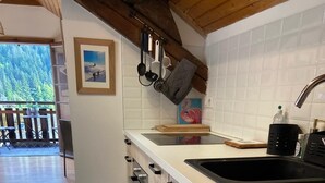 A kitchen with a wooden countertop, a black sink, and a view of a balcony with outdoor furniture. - 50m from resort center, 3rd floor, balcony, parking, tv, ski locker, 25m², Le Grand Bornand (Le Grand-Bornand)