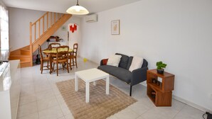 A living room with a sofa, coffee table, and a dining area with chairs and a table. There is a staircase leading to another level. - Beautiful home in Aubignan (Aubignan)