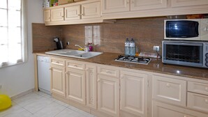 A kitchen with beige cabinets, a double sink, a stove, a microwave, and a dishwasher. - Beautiful home in Aubignan (Aubignan)