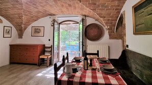 A dining area with a checkered tablecloth, a brick ceiling, and a view through an open door to an outdoor area. - Holiday, where Tuscany is still authentic. 16th c. Villa Infinity Pool: Cipresso (Toscana)