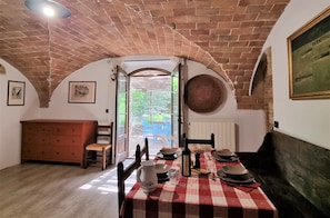 Enjoy meals in this charming dining area with a brick ceiling, a woven basket, and a view of the garden through the glass door.