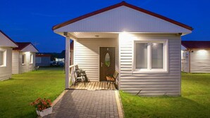 A single-story mobile home with a porch, a door marked with the number 5, and a small garden area with potted plants. - Awesome home in Sarbinowo (Sarbinowo)