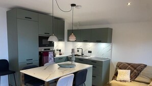 A compact kitchen with a marble countertop, a dining area with two chairs, and a sofa with a blanket. - 100m from resort center, 3rd floor, balcony, tv, ski locker, 35m², Le Grand Bornand (Le Grand-Bornand)