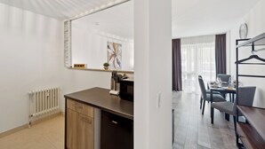 Een moderne keuken met een ingebouwde vaatwasser, een eethoek met tafel en stoelen, en een grote spiegel boven het aanrecht.