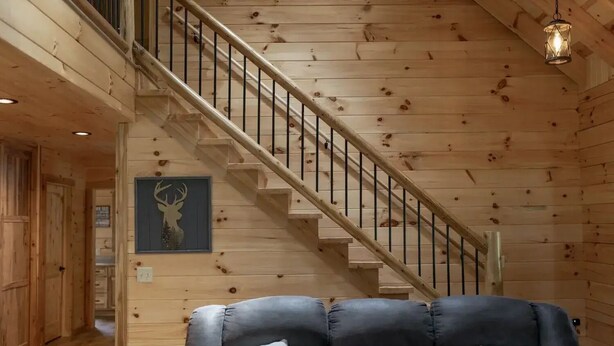Ein Holzinterieur mit einer Treppe, einem Ledersofa und einem aufgehängten Hirsch-Dekorationsobjekt.