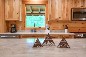 A kitchen with wooden cabinets, a marble countertop, and three wooden signs with words 'Discover,' 'Adventure,' and 'Explore.'