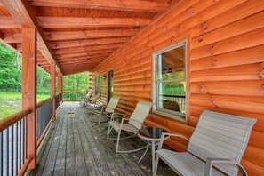 A wooden cabin with a porch, rocking chairs, and a view of the forest.