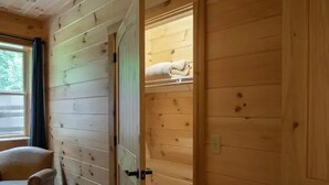 Ein Holzinnenraum mit einer Tür zu einem Zimmer mit Bett und Fenster.